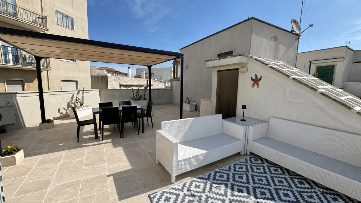 Die Pergola mit dem Esstisch und den weißen Sofas